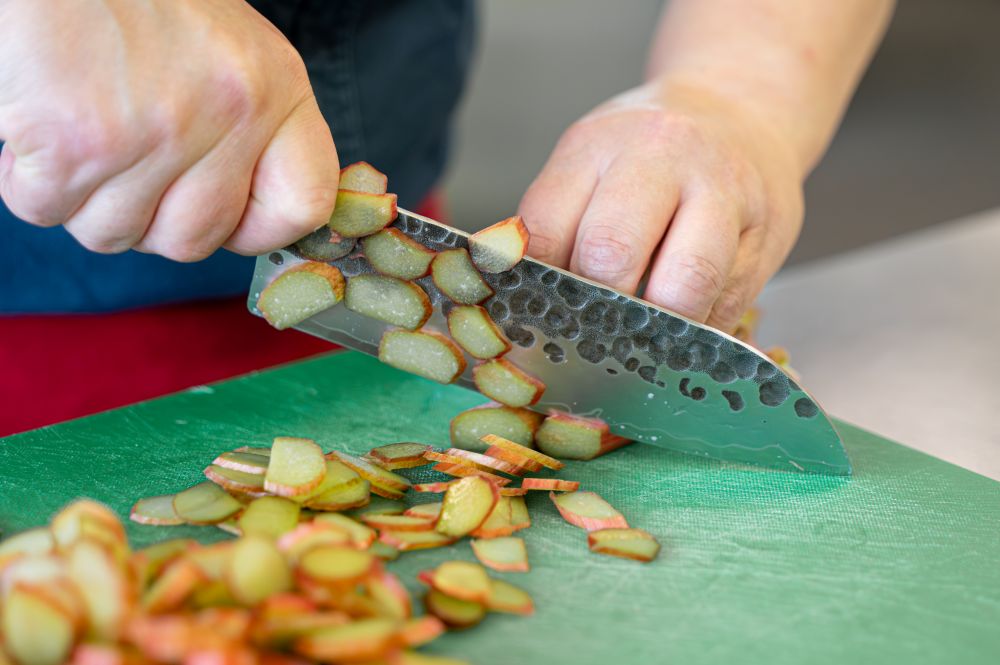 A photograph of a chef slicing a vegetable