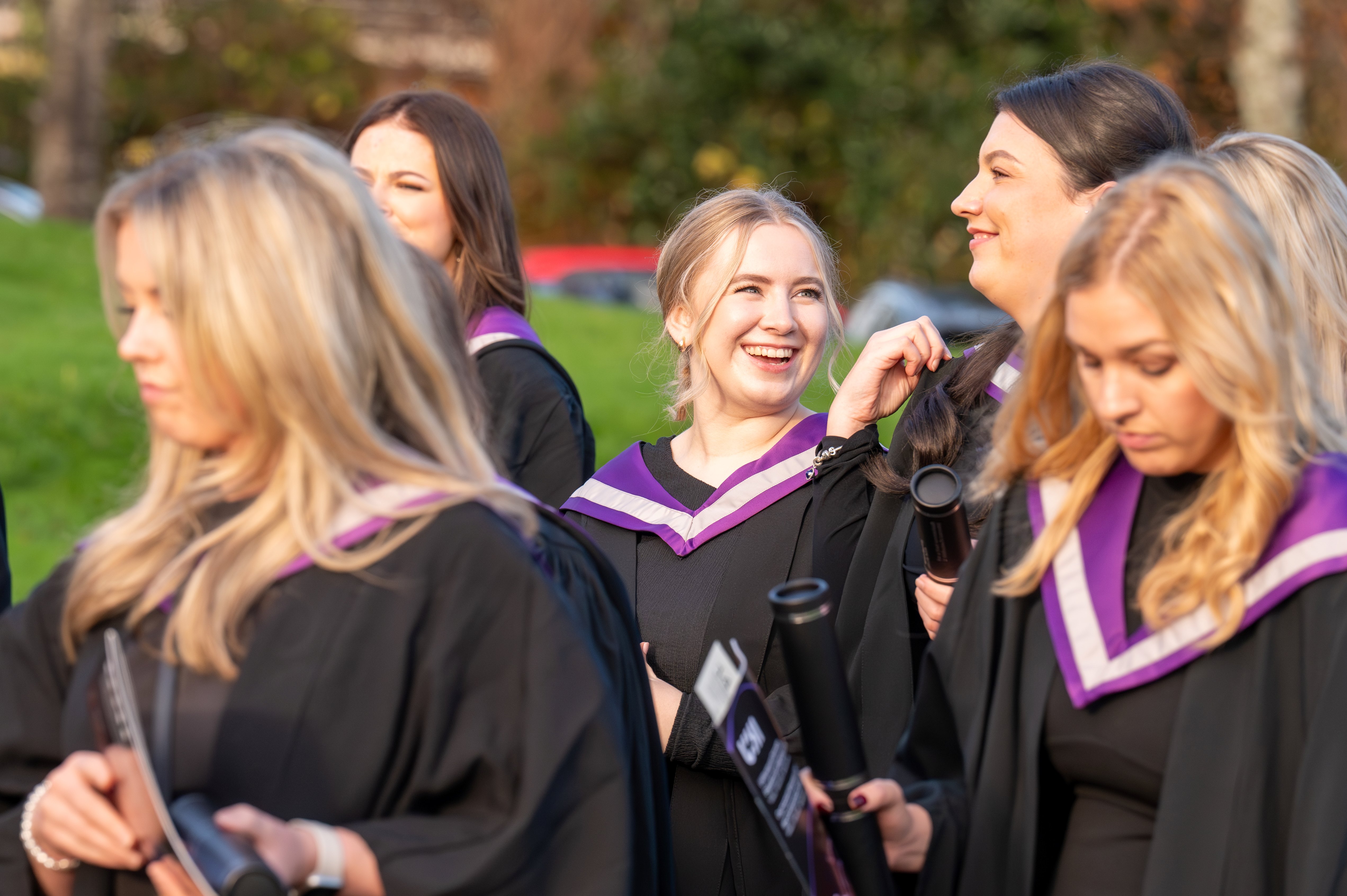 smiling students leaving graduation with their scrolls