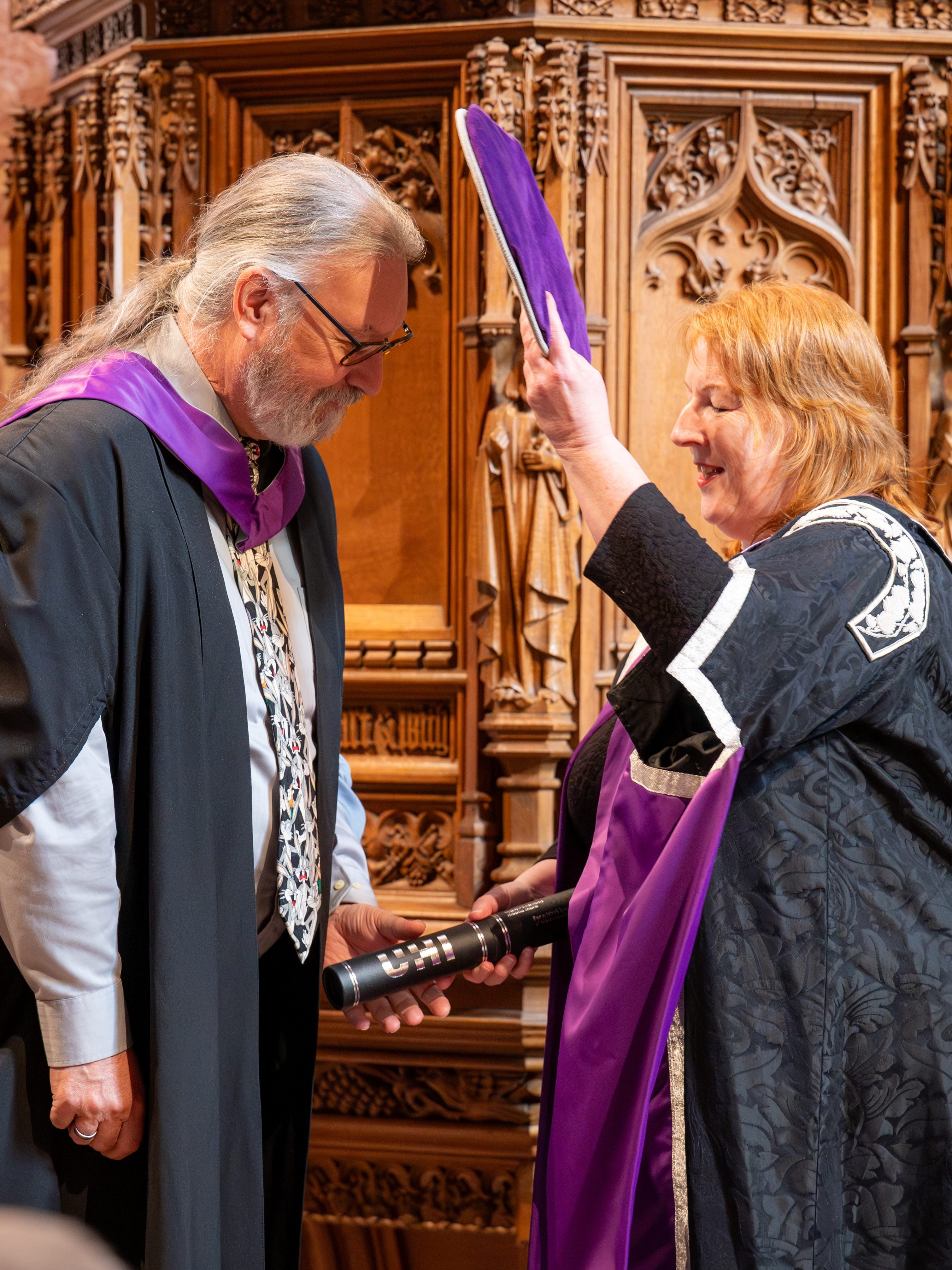 Graduate receiving their scroll whilst being doffed