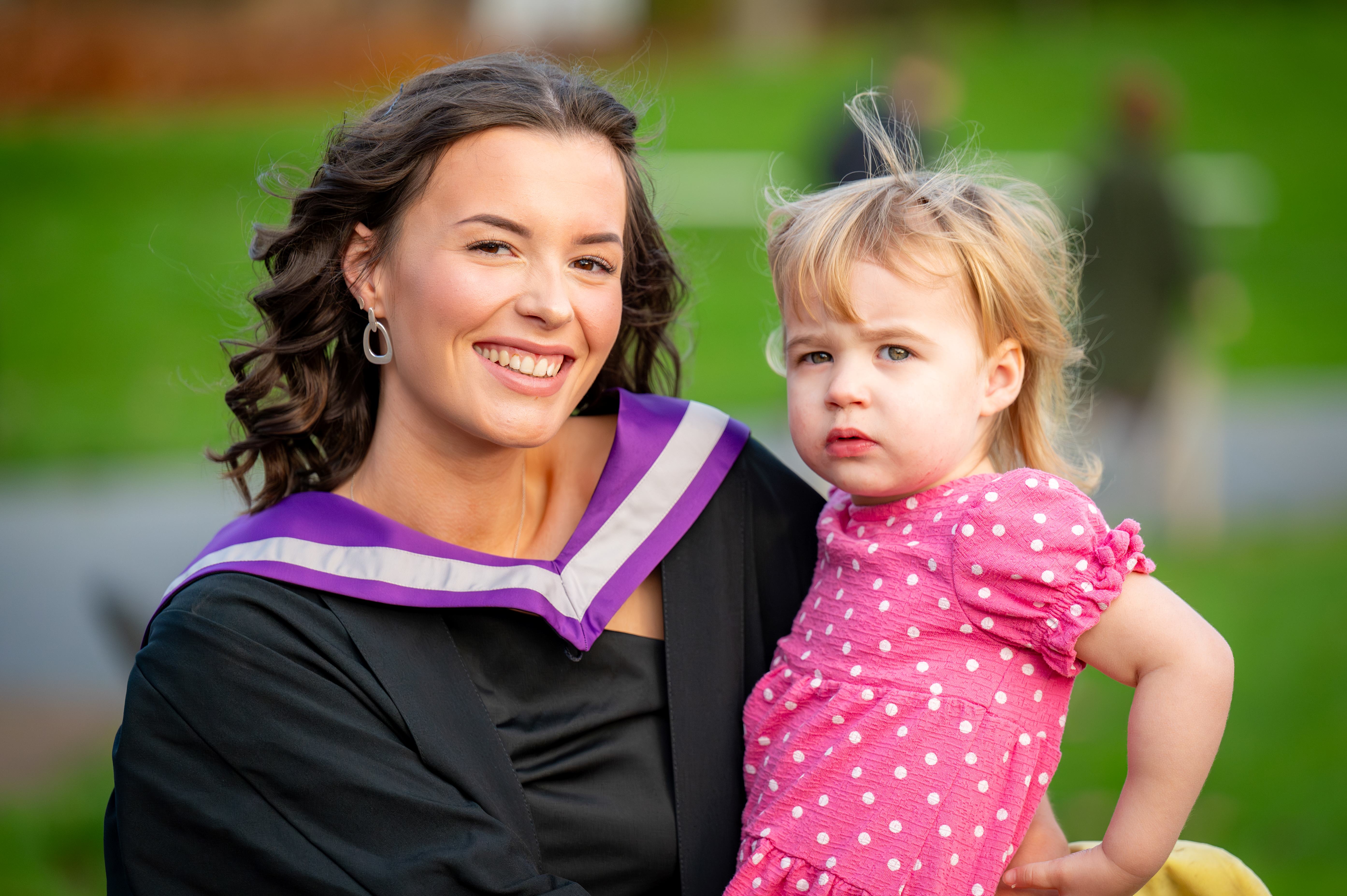 Graduate holding her young child
