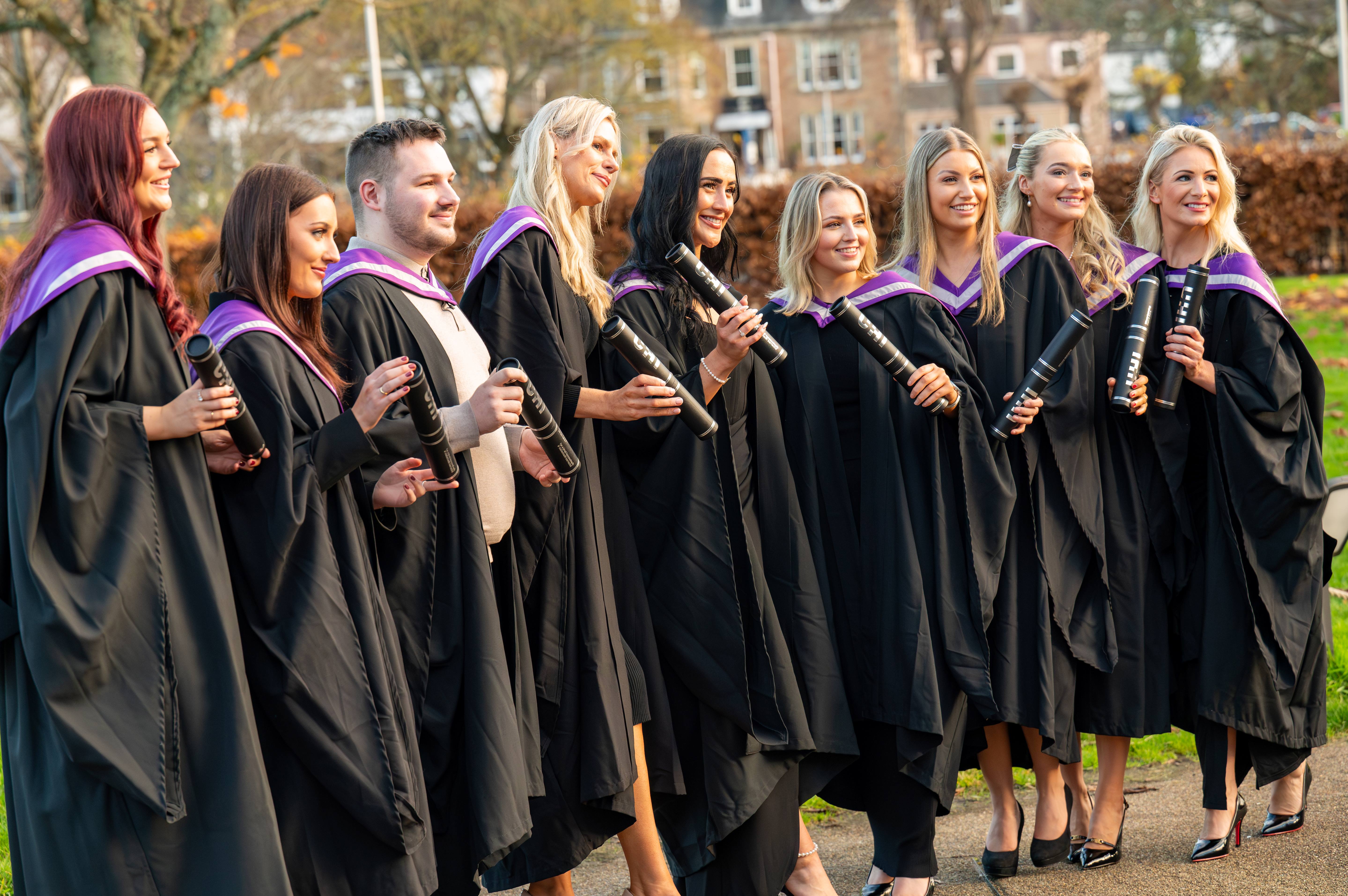 Group of students in robes holding tubes
